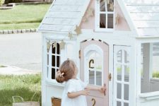 a tiny and cute white and pink kids’ playhouse with a pink door, a star garland and blooms is ideal for a little kid