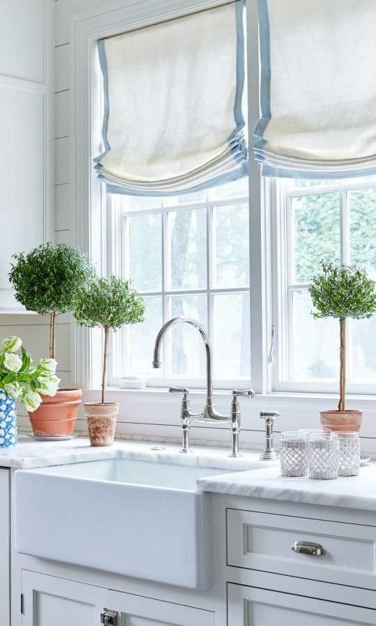 a traditional kitchen with white and blue Roman shades that add interest and coziness to the space