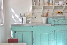 a vintage kitchen with shabby light blue and white furniture, a small dining set and pastel porcelain on top the cabinets