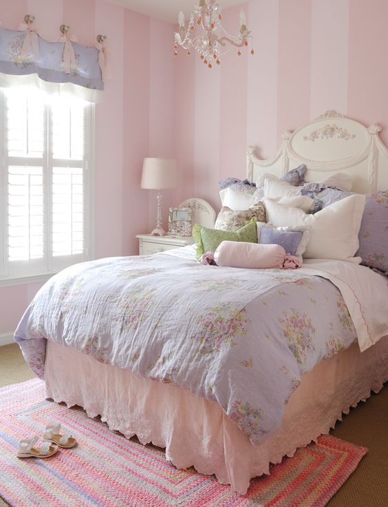 a vintge to shabby chic kid's bedroom with pink striped walls, a refined white bed, pastel floral bedding, a purple curtain and a crystal chandelier