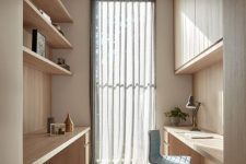 a welcoming minimalist home office with a built-in slek storage unit, open shelves, built-in desks and a blue chair plus a curtain