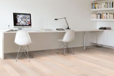a white minimalist home office with bookshelves, a long desj and white chairs plus a black table lamp is a cool space