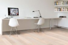 a white minimalist home office with bookshelves, a long desj and white chairs plus a black table lamp is a cool space