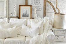 a white shabby chic living space with a gallery wall, a white sofa, a shabby sideboard and a wooden chest