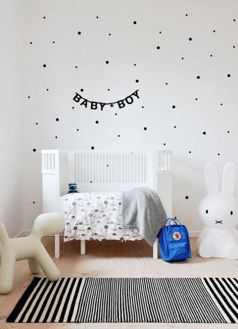 an airy Scandinavian kid's room with a polka dot wall, a white bed, some printed textiles and cool and simple toys