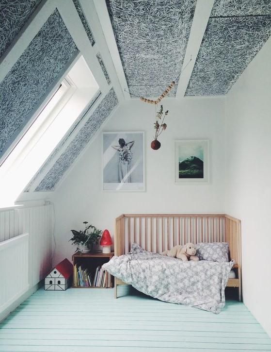 an attic nursery with a mint floor, a black and white paneled ceiling, a crib and some toys and storage units