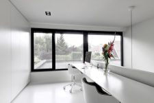an ultra-minimalist home office in black and white, with a floor to ceiling window, a floating shared desk and black and white chairs