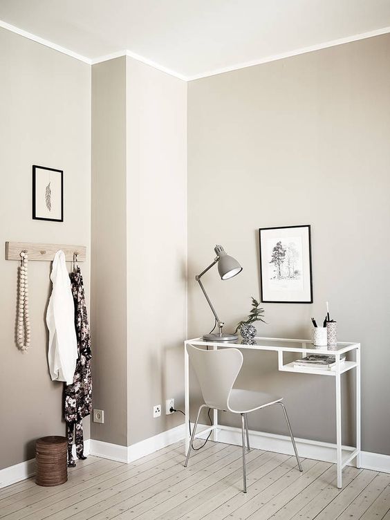 a Nordic space with a white Vittsjo desk, a creamy chair, a grey lamp and some pen jars and a black and white artwork