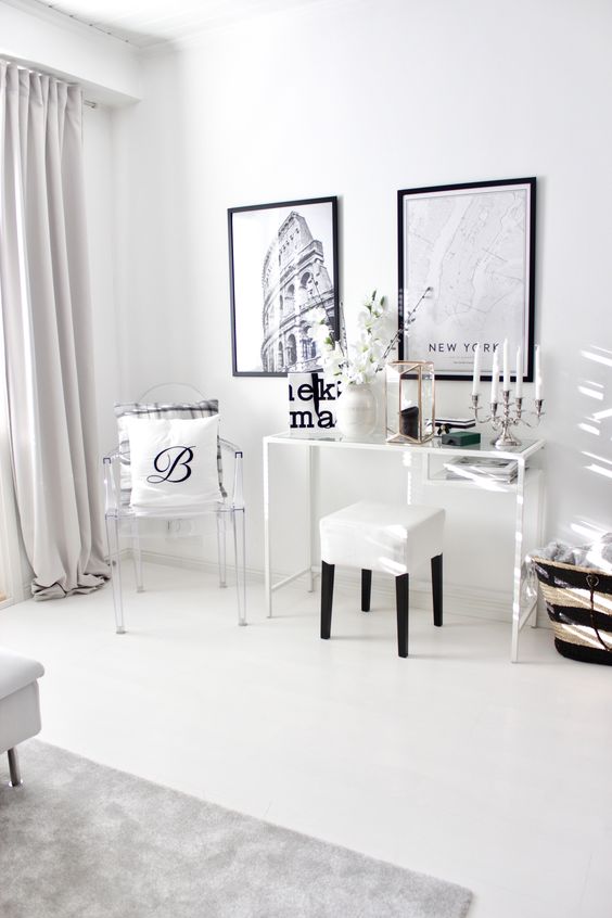 a Scandinavian room with a white Vittsjo desk, a white stool and a clear chair, a black and white gallery wall, a black candle and blooming branches