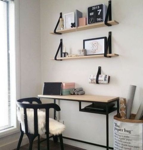 a Scandinavian working space with open shelves and a Vitssjo desk with a wooden countertop, a black chair and some art and books