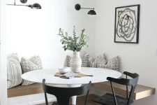 a beautiful Scandinavian dining space with a floating bench, a round table, black chairs, black sconces and a graphic art