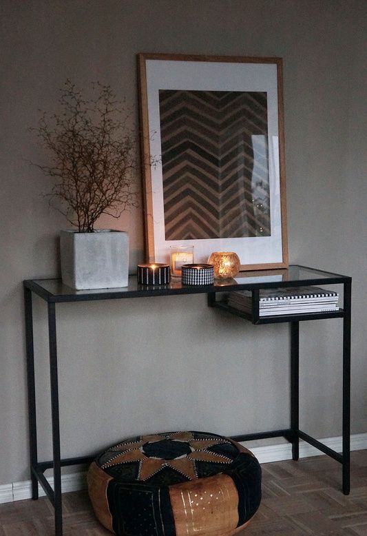 a beautiful moody space with a black Vittsjo table, a boho pouf, candles, a potted plant and a chevron artwork is lovely