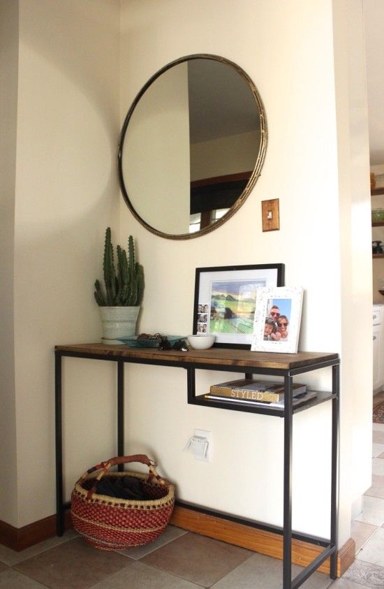 a boho entryway with a Vittsjo table renovated with a wooden desktop, a woven basket, a potted cactus and some artworks and photos
