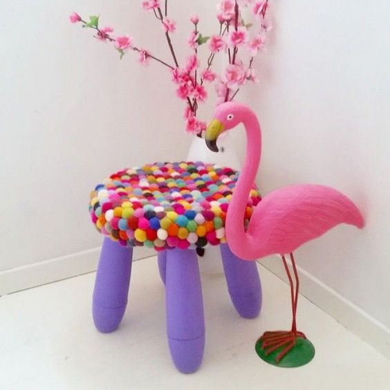 a bright purple IKEA Mammut stool covered with bright pompoms is soft and cute and very colorful