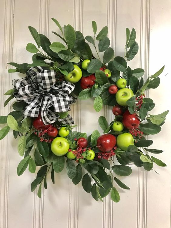 a bright wreath of foliage, green and red apples and a plaid bow is a cool decoration in farmhouse style