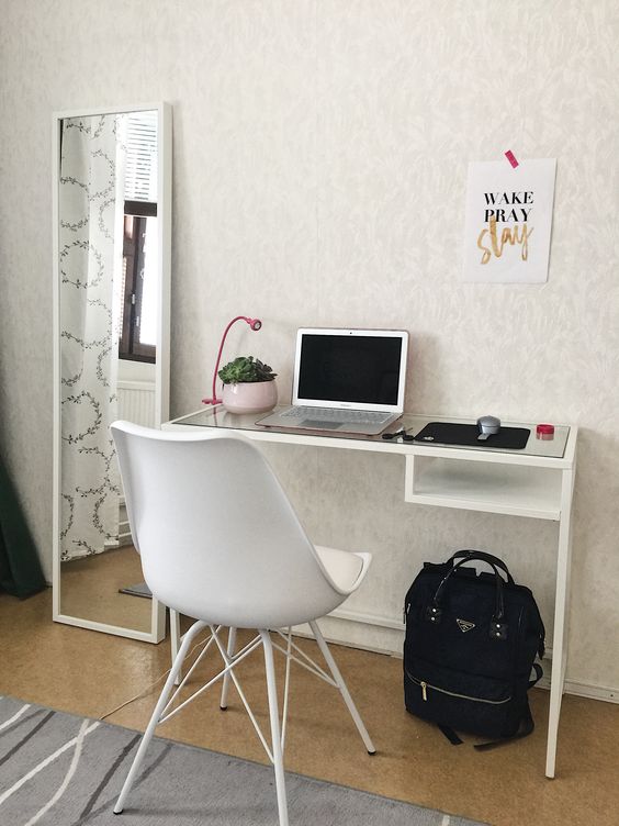 a chic and small working and studying space with a white Vittsjo desk, a white chair, a potted plant and a small pink table lamp
