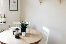 a cozy dining nook with a stained round table, white chairs, open shelves and some greenery in pots has everything necessary