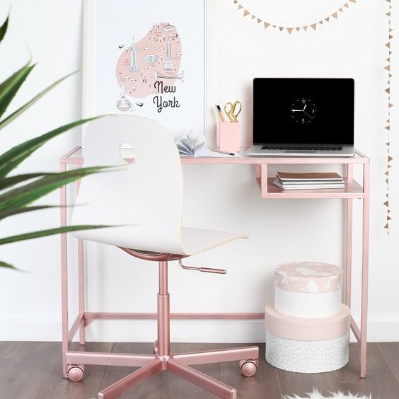 a girlish working space with a pink Vittsjo table, a white and pink chair, stacked boxes, an artwork and some other pink accessories