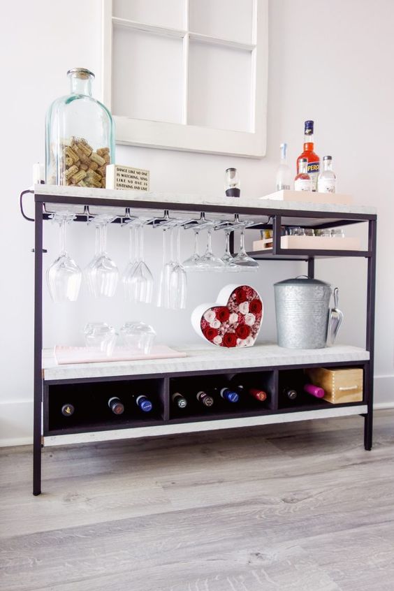 a home bar made of an IKEA Vittsjo table, with marble adhesives, an additional shelf for storing wine, a floral box and a jar with corks