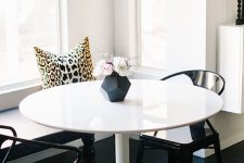 a little glam dining space with a built-in bench, a round table, black chairs, a gilded chandelier, printed elements