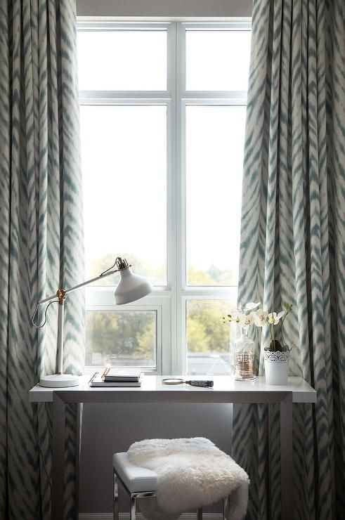 a lovely makeup space by the window, with a tiny vanity, a stool and a white IKEA Ranarp table lamp