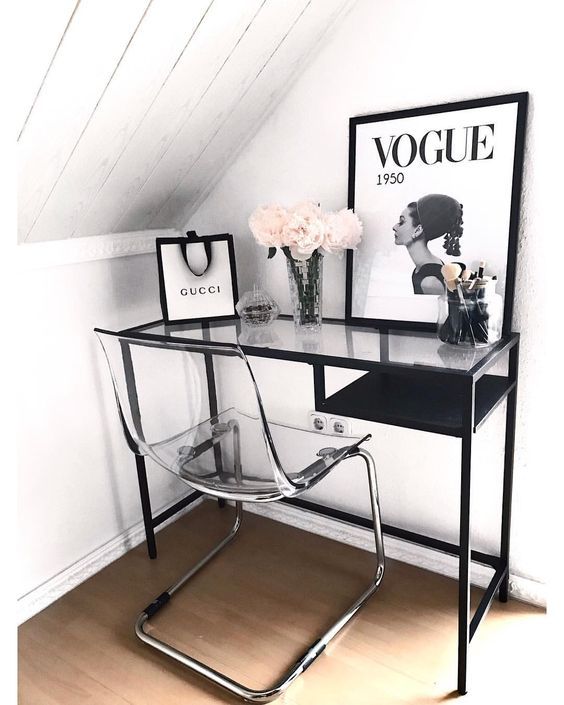 a small attic working and makeup space with a black Vittsjo desk, a clear chair, some art, blooms is amazing