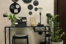a small makeup or working space with a black Vittsjo desk, a black stool, potted greenery, a whole gallery wall of mirrors is all cool