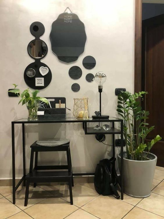 a small makeup or working space with a black Vittsjo desk, a black stool, potted greenery, a whole gallery wall of mirrors is all cool