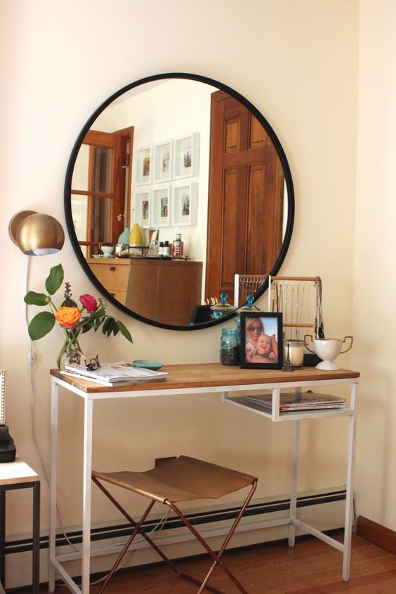 a stylish conole table of an IKEA Vittsjo desk, with a wooden tabletop to make it more rustic-like, with accessories, decor, candles and a round mirror in a black frame