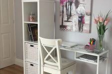 a working space with a white storage unit with crates, a white Vittsjo desk with a marble tabletop, a white chair, pink tulips and a bright artwork