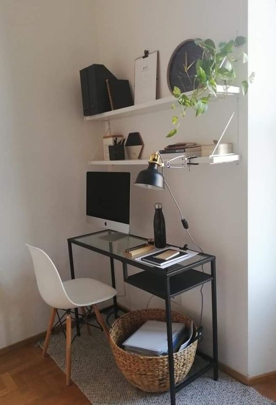 an elegant Scandinavian working nook with open shelves, a black Vittsjo desk, a white chair, a basket for storage, a clock and some greenery