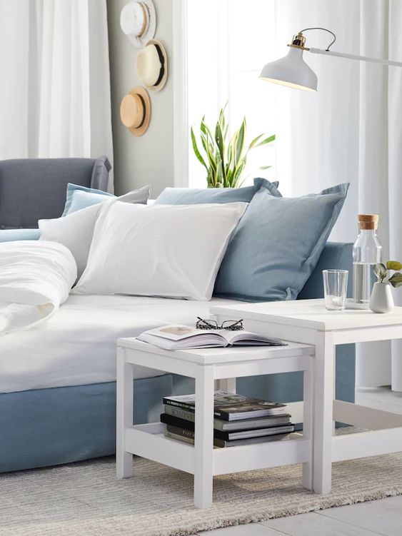 an ethereal blue and white coastal bedroom with a hat display, IKEA Ranarp floor lamp and mini white tables