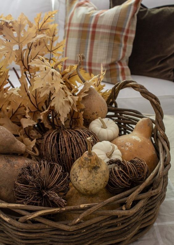 a basket with vine and faux pumpkins, pears, fall leaves and gourds is a rustic decoration with a strong natural feel
