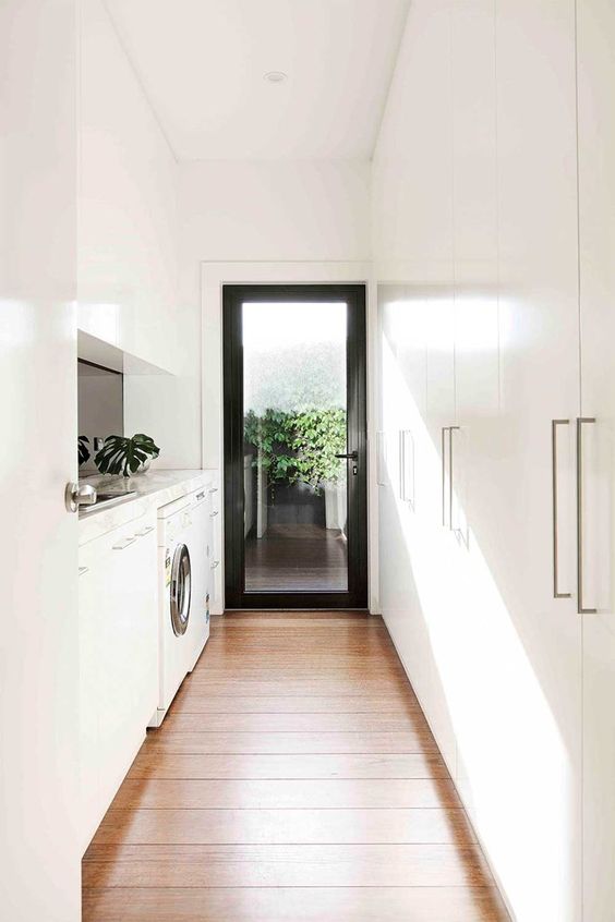 a beautiful white laundry with sleek cabinets, tall wardrobes, a washing machine and a dryer, a concrete backsplash