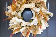 a bold fall wreath made of corn husks, bright faux branches and wheat is a lovely idea to decorate your front door