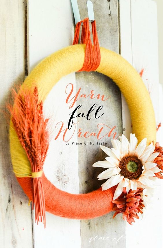 a bold yarn fall wreath covered with orange and yellow yarn, with dried blooms and orange wheat