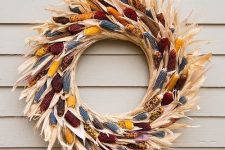 a bright and catchy fall wreath made of corn husks with colorful Indian corn cobs inside is a gorgeous solution