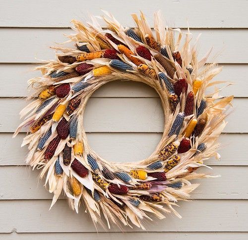 a bright and catchy fall wreath made of corn husks with colorful Indian corn cobs inside is a gorgeous solution