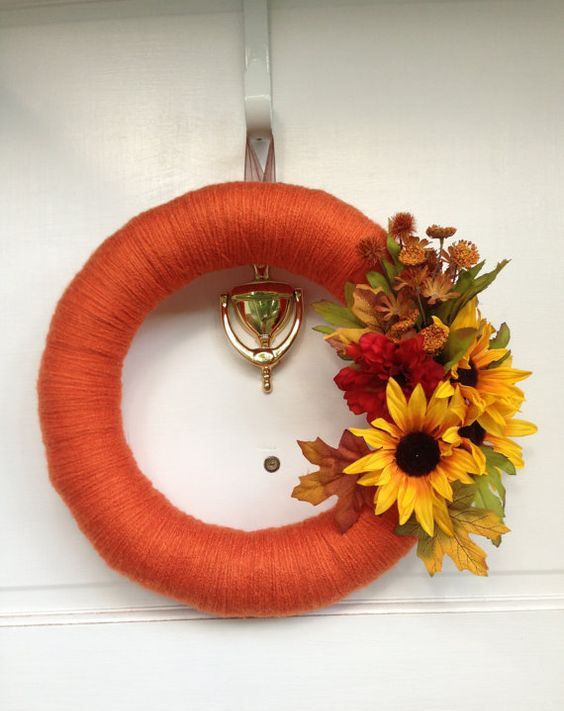 a bright fall wreath covered with orange yarn, with faux blooms and leaves is a fun and bold idea