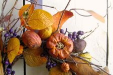 a bright fall wreath with twigs, berries, faux veggies and fruits, bright leaves is a harvest-inspired piece