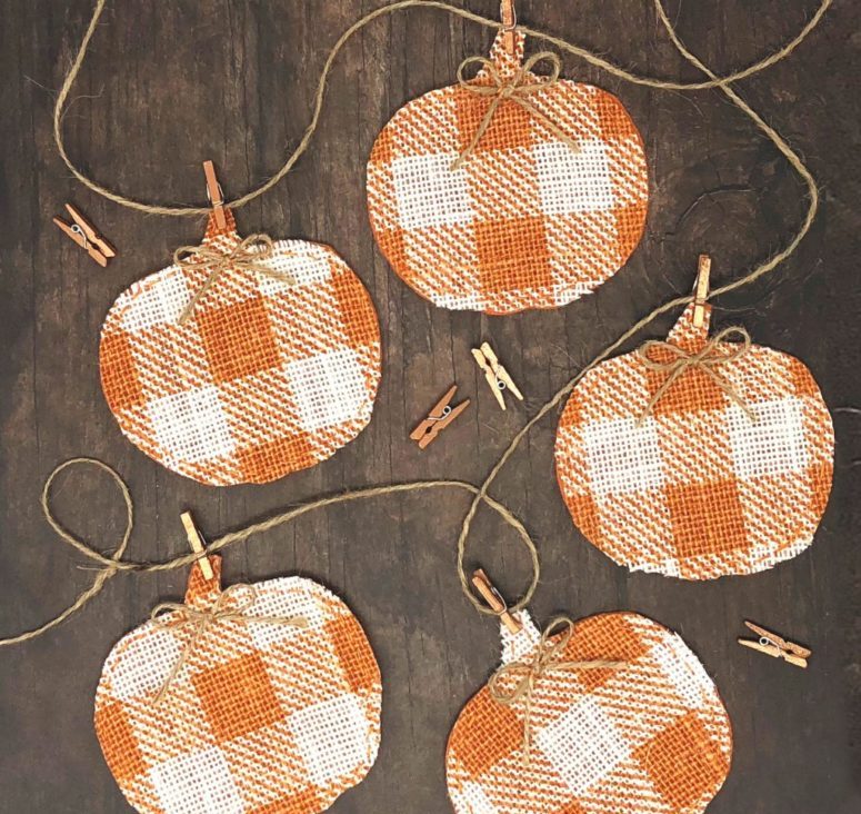 a bright pumpkin banner made of buffalo check burlap and twine is a fun and cool decor idea for fall and Thanksgiving