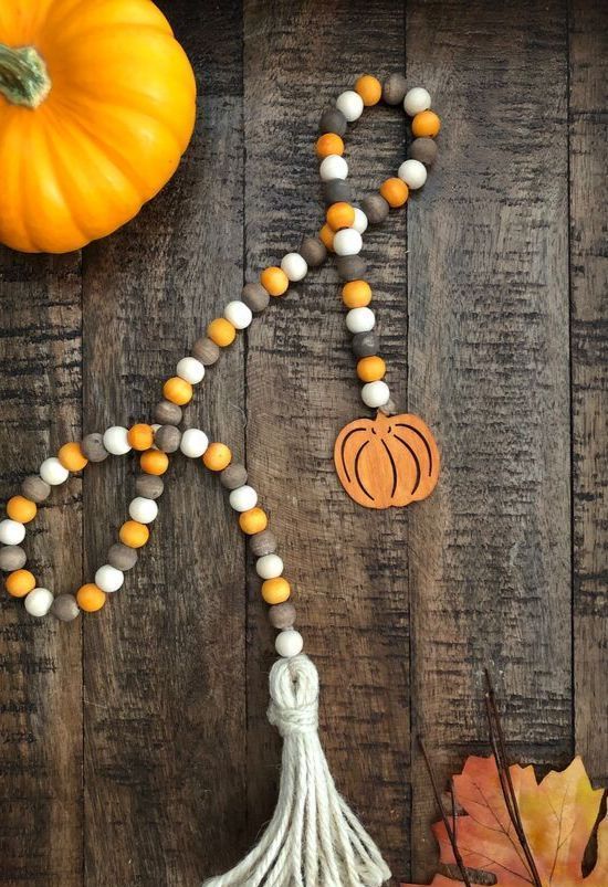 a bright wooden bead garland with a small wooden pumpkin and a tassel is a stylish and chic idea for fall and Thanksgiving