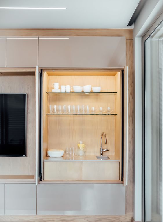 a built-in minimalist home bar of plywood, with glass shelves, a sink and drawers is simple and cool