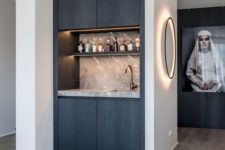 a built-in minimalist home bar with a marble backsplash, open built-in shelves and lights and storage units