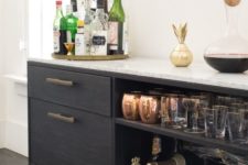 a chic black home bar with open and closed storage compartments, gold touches and a gold tray is elegant