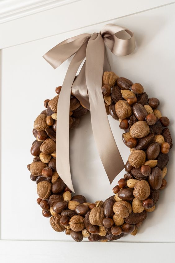 a chic natural fall wreath made of glossy nuts and topped with an elegant grey ribbon bow is a lovely and organic decor idea
