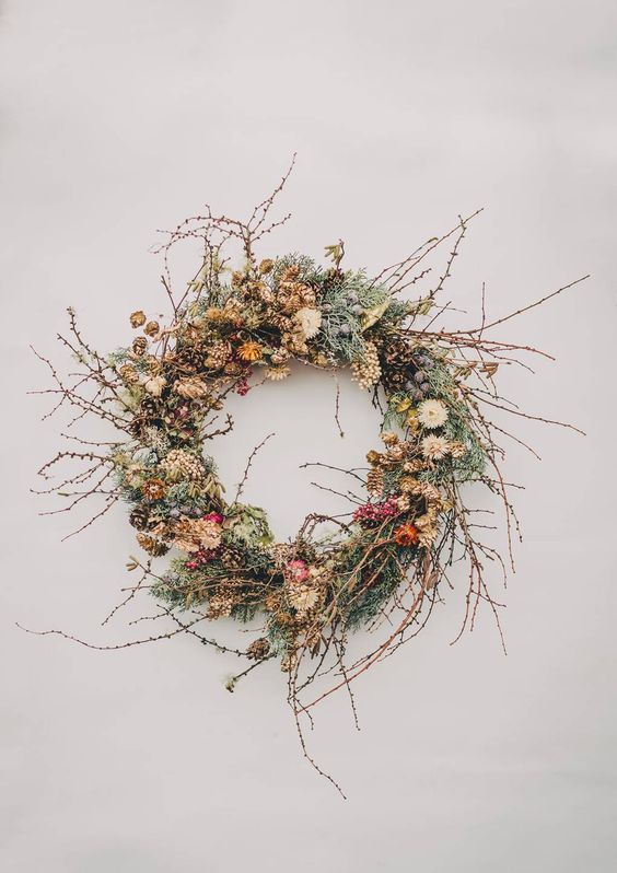 a chic twig fall wreath with moss, berries, twigs, dried leaves and blooms plus pinecones for a fall feel