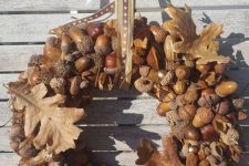 a cool all-natural fall wreah of acorns and nuts, with large faux leaves and a printed ribbon on top is a chic solution