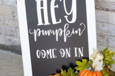 a cool black and white fall sign decorated with faux leaves ad pumpkins is a cool fall decoration for outdoors