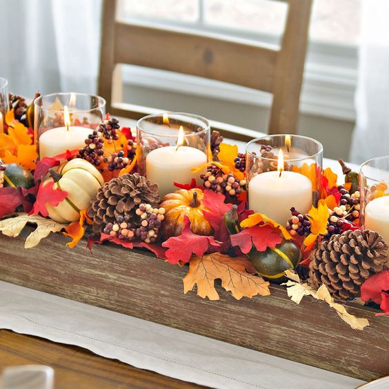 a fall centerpiece of a wooden box with pinecones, faux leaves, berries, faux gourds and candles is a bold idea